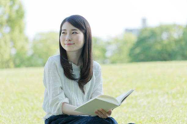 istock A woman reading a book outdoors 976811896
