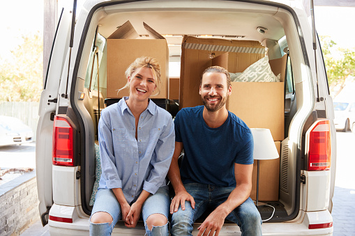 Portrait Of Couple Sitting In Back Of Removal Truck On Moving Day