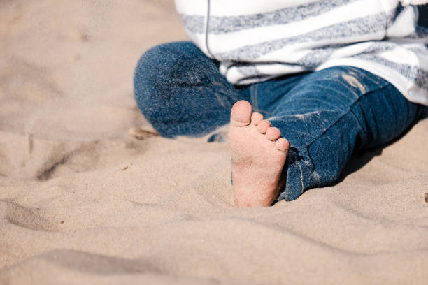 istock baby hand playing with sand on the beach 976825822