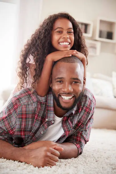 Photo of Portrait Of Daughter Lying On Fathers Back In Lounge