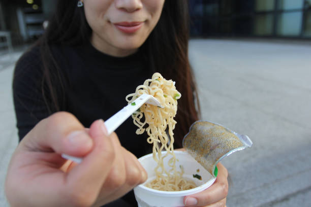 young woman hand holding plastic fork of instant noodles, sodium diet high risk kidney failure, healthy eating - beat the clock fotos imagens e fotografias de stock