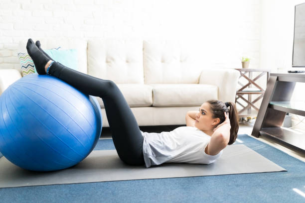 istock Woman doing sit up with exercise ball at home 976907254