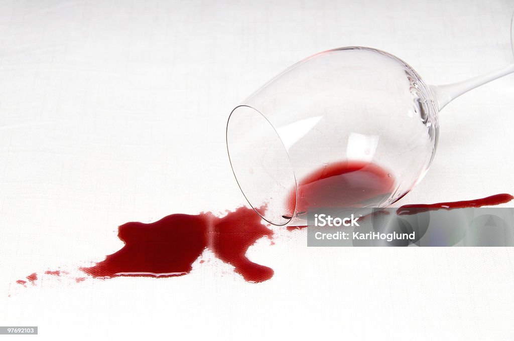 A glass of red wine tipped over on a white background Spilling red wine on the tablecloth Spilling Stock Photo