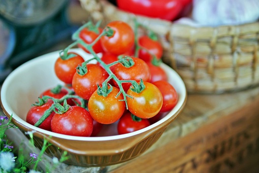 Fresh, raw vegetables for cooking:red and juicy vine-ripened cherry tomatoes in a ramekin. Selective focus.