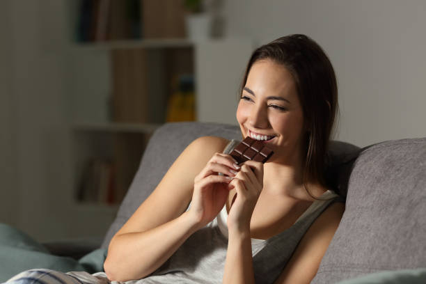 Woman enjoying eating chocolate in the night stock photo