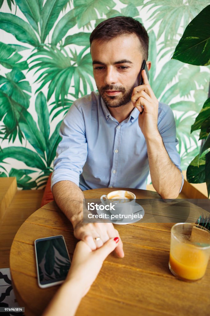 Couple holding hands Couple in cafe using phones Personal Perspective Stock Photo