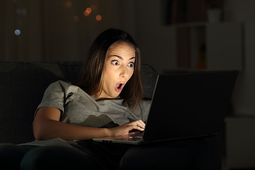 Mujer sorprendida ver contenido online en la oscuridad photo