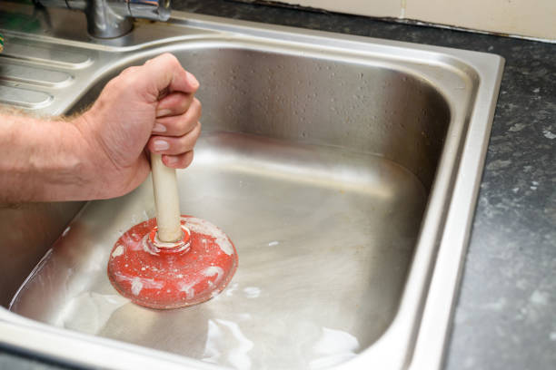Plunger in a Sink Man holding a plunger with one hand and water in sink, used to clean a clogged / blocked kitchen sink clogged stock pictures, royalty-free photos & images