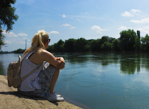 Little cute girl in a bathing suit is resting on the lake. the child's feet are washed with water, and green reeds grow behind