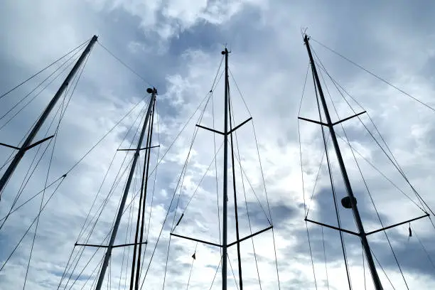 Ship masts over blue cloudy sky background