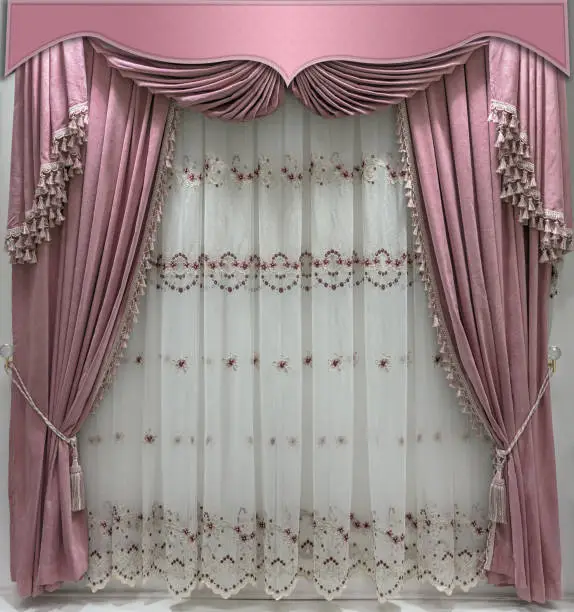 Interior decoration in gentle pink tones. Soft velvet curtains with fringe along the edge, combined pelmet and light tulle with embroidery.