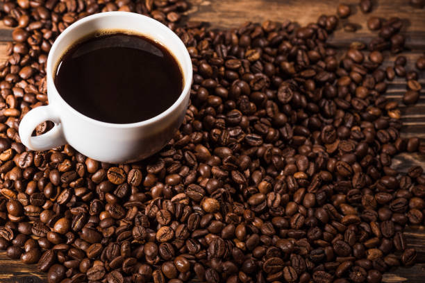istock high angle view of cup with coffee beans on rustic wooden table 977065564