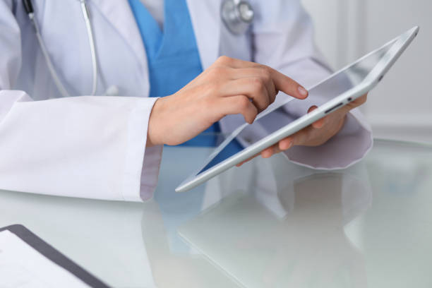 istock Female doctor using tablet computer while sitting at the workplace, close-up of hands. Medicine, healthcare and help concept 977070970