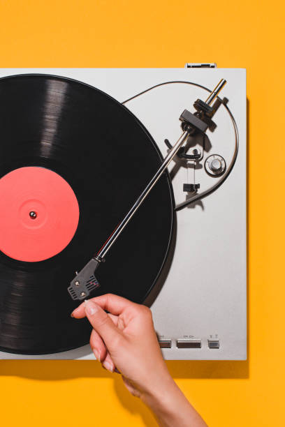 cropped shot of woman turning on vinyl player isolated on yellow cropped shot of woman turning on vinyl player isolated on yellow retro turntable stock pictures, royalty-free photos & images