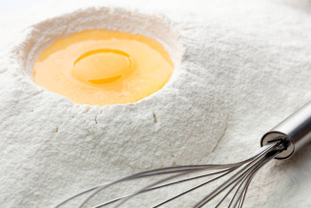 liquid raw chicken egg on heap of wheat flour