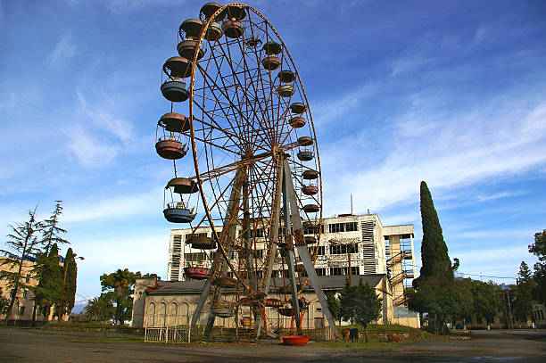 Abkhazia, rusty destroy ferris wheel  and war-ravaged spa-hotel background stock photo