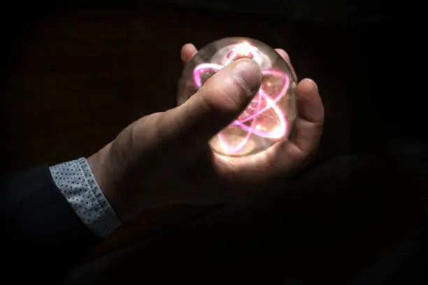 Holding atom in fortune teller magic crystal ballHolding atom in fortune teller magic crystal ball