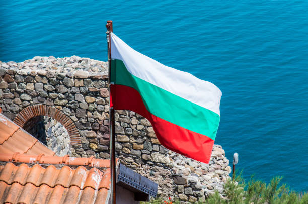 istock Bulgarian flag with blue ocean and historic ruins in background 977122888