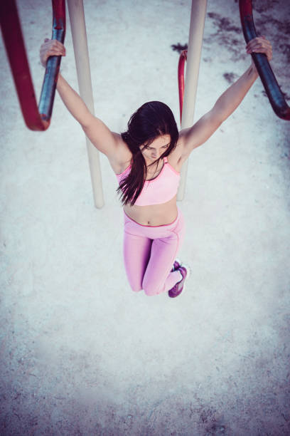 istock Attractive Female Athlete Doing Pull-Ups in Public Outdoor Gym 977123050