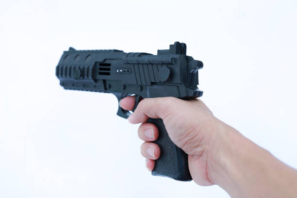 istock Hand holding black plastic toy gun on white background. 977163340