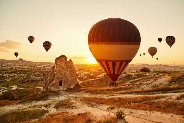 воздушные шары, летящие на закате, каппадокия, турция - cappadocia hot air balloon turkey basket стоковые фото и изображения