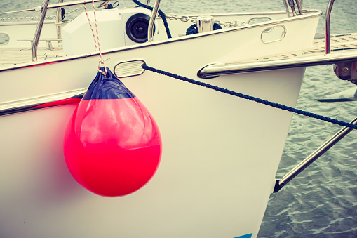 Yachting, sailing conept. Sailboat in the sea with many red fenders buoy.