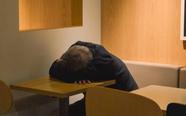 istock Old man sleeps on the table in cafe after hard working day 977251572