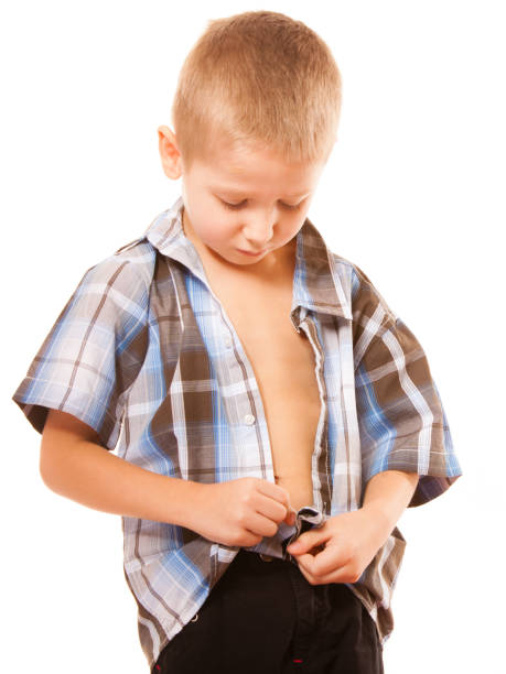 istock little boy buttoning on shirt, isolated on white 977256234