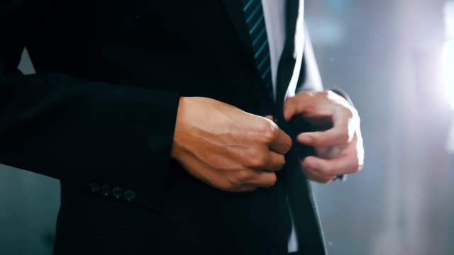 businessman in suit fastening button on jacket