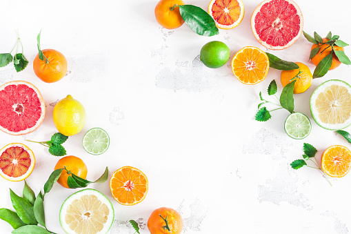 Fruit background. Colorful fresh fruits on white table. Orange, tangerine, lime, lemon, grapefruit. Flat lay, top view, copy space