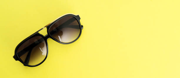 istock Sunglasses on yellow background - copy space summer concept 977356060