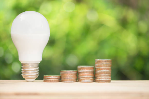 istock LED build and growing coins stack with warm sun lighting and green nature background for energy saving concept 977415682