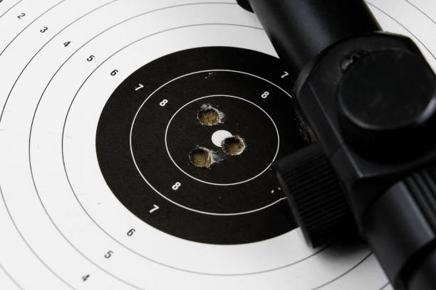 istock Shooting and pneumatic weapon. Shield and hits with lead bullets on a wooden table. Dark background. 977425904
