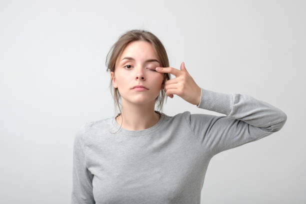The woman is touching her eye to show that she has problem with eyesight. Health trouble. The woman is touching her eye to show that she has problem with eyesight. Health trouble. Concept of miopia or astigmatism squint eyes stock pictures, royalty-free photos & images