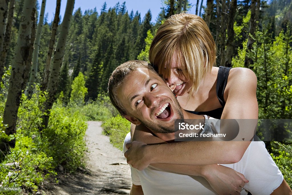 Giovane ragazza Portare a cavalluccio con ragazzo Mordere il suo orecchio - Foto stock royalty-free di Abbigliamento casual