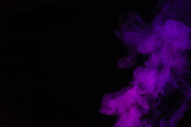 Photo of black background with purple smoke with copy space