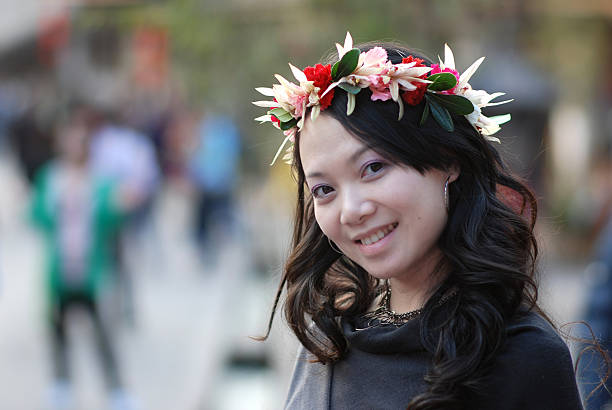 Portrait of a beautiful young woman in a flower wreath crown with a bouquet of wildflowers at summer sunny day