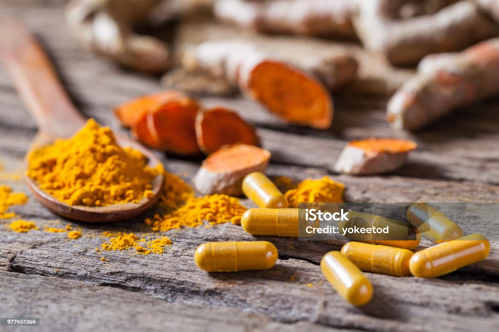 Turmeric powder, turmeric capsule and turmeric on wooden background Turmeric Stock Photo