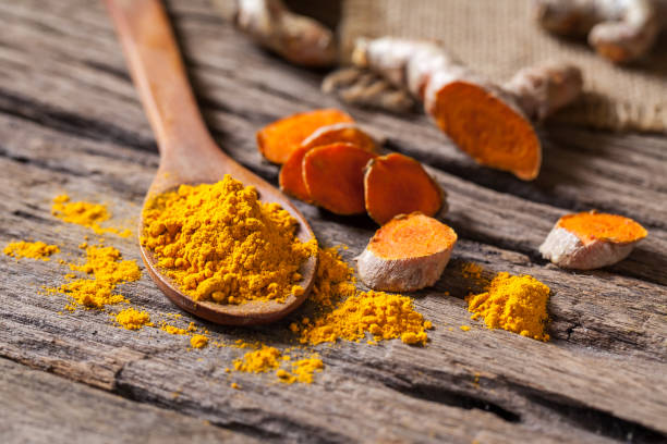 istock Turmeric powder and turmeric on wooden background 977451746