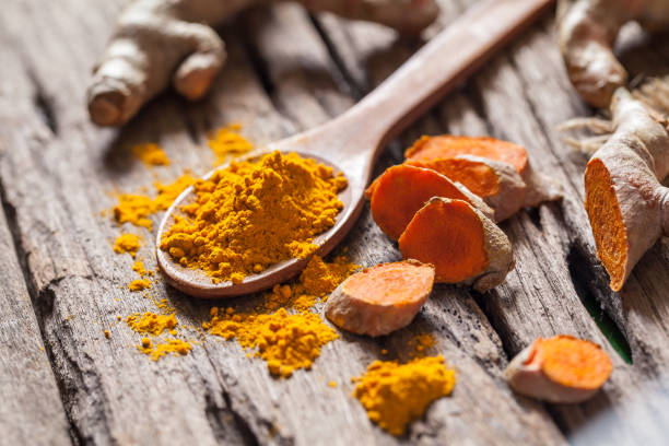 istock Turmeric powder and turmeric on wooden background 977451852