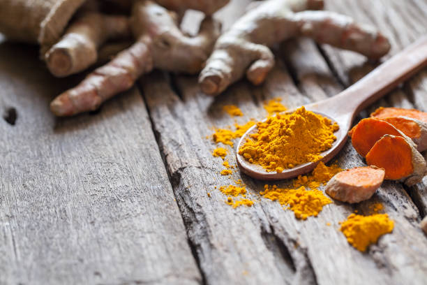 istock Turmeric powder and turmeric on wooden background 977454378