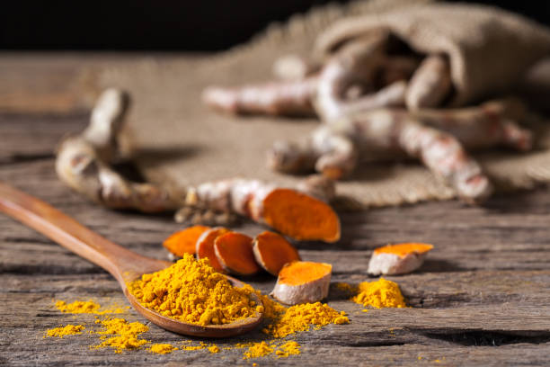 istock Turmeric powder and turmeric on wooden background 977454464