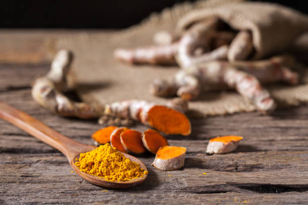 istock Turmeric powder and turmeric on wooden background 977454756