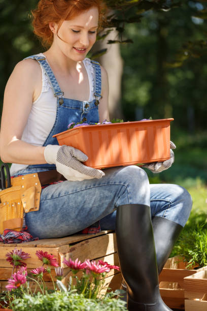 istock Woman outside holding flower pot 977480250