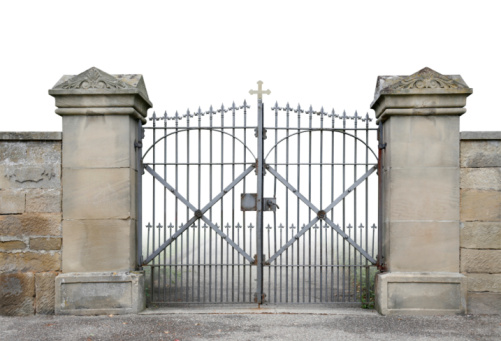 entrance of a graveyard with a wrought-iron gate and stone wall detail in gradient back with clipping path