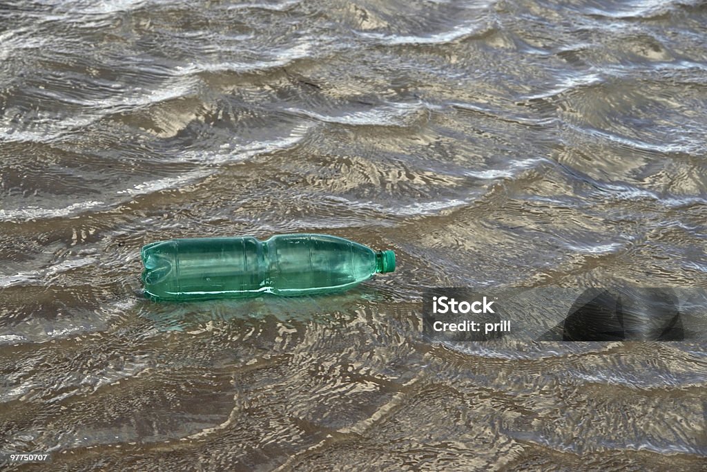 floating green bottle pollution theme with a green plastic bottle floating on water surface Sea Stock Photo