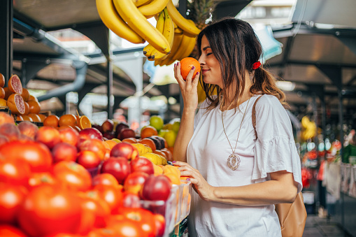 Woman smelling orange fruit at the market