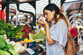 Young cheerful woman smelling garlic at the market