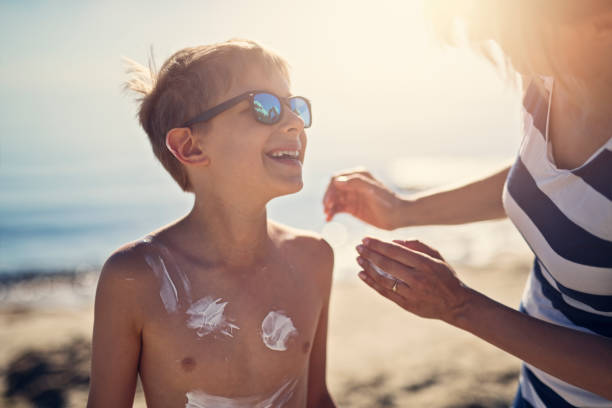 madre che applica la protezione solare al figlio - sun protection foto e immagini stock