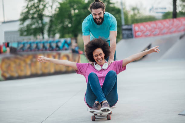 istock Handsome man pushing skateboard with woman sitting on it 977552942